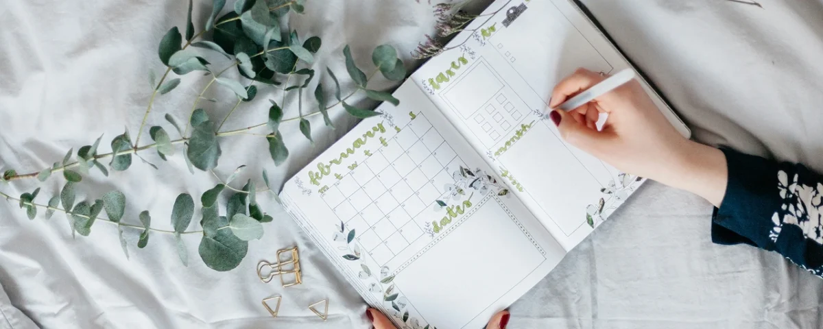 Agenda Bullet Journal aperta su pagina mensile decorata con fiori e calendario scritto a mano
