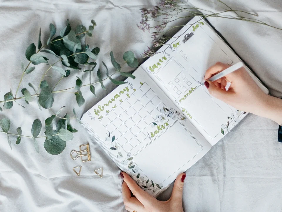 Agenda Bullet Journal aperta su pagina mensile decorata con fiori e calendario scritto a mano