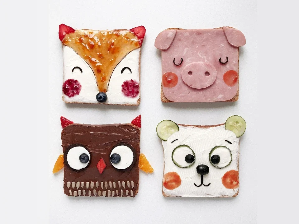 Fette di pane decorate con ingredienti colorati per rappresentare animali come volpe, maiale, gufo e orso, create dall’artista Daryna Kossar